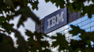 Photo of the IBM Building (IBM) seen through the canopy of a tree.  The IBM logo is in large letters on the side of the building.
