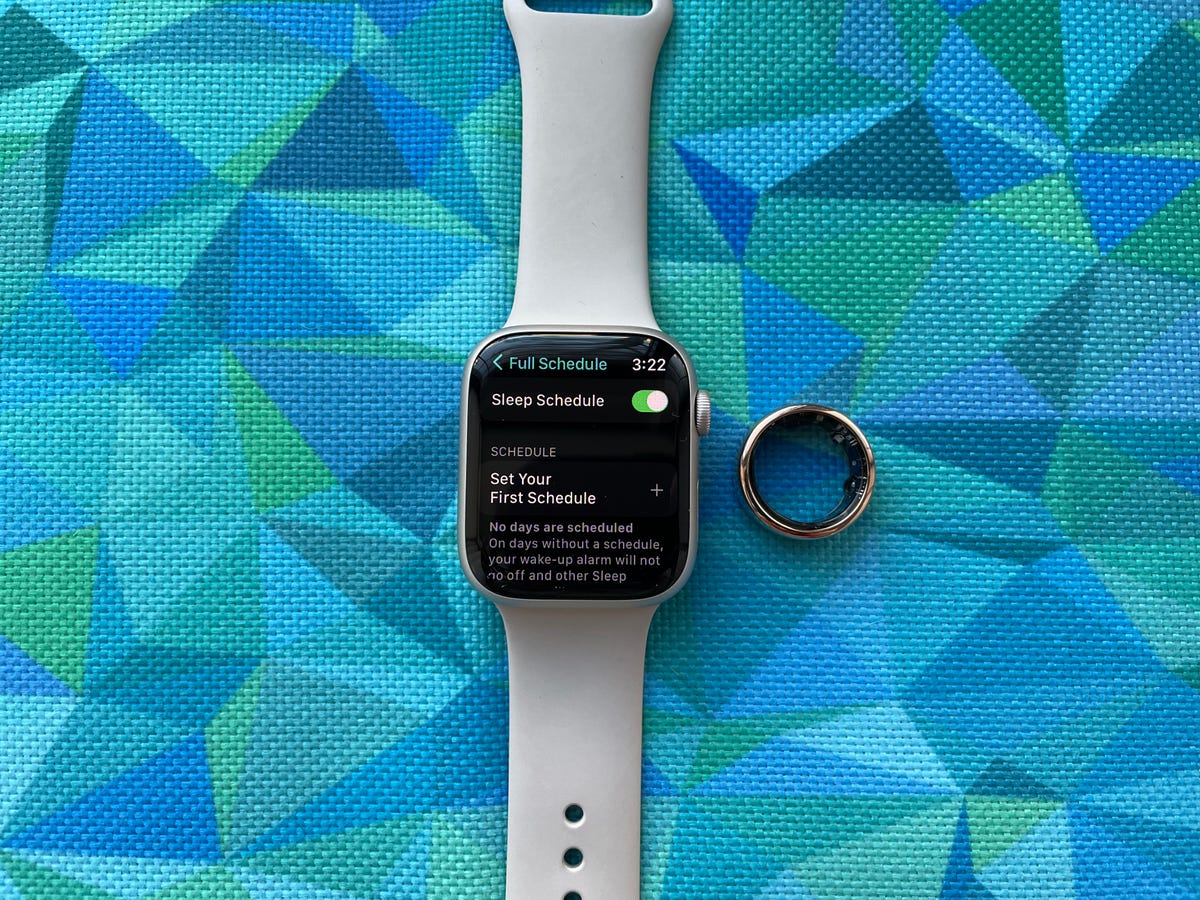 Apple Watch Series 8 next to the Oura ring on a blue background