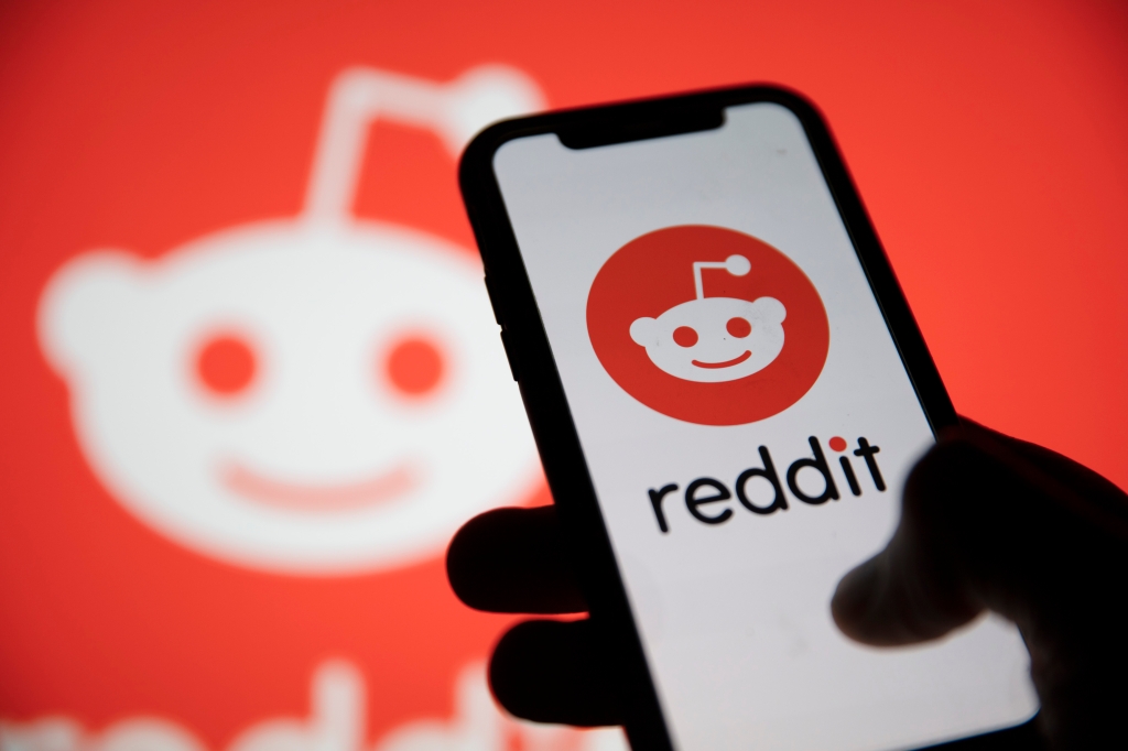 Reddit logo displayed on smartphone with the Reddit logo in the background